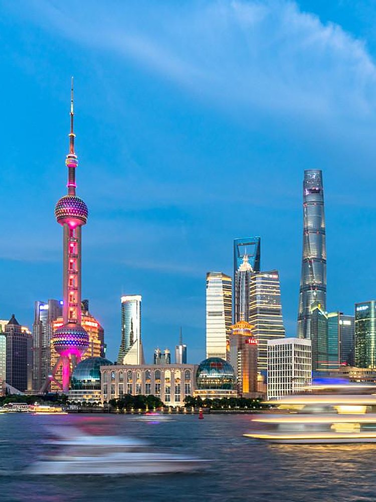 The Pudong skyline across the Huangpu River at blue hour, the Oriental Pearl Tower and Shanghai Tower lit